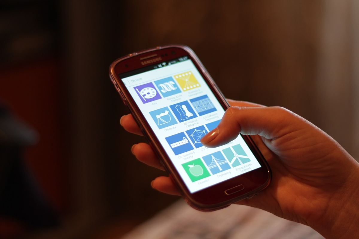 Hand hält ein Smartphone mit App-Symbolen auf dem Bildschirm